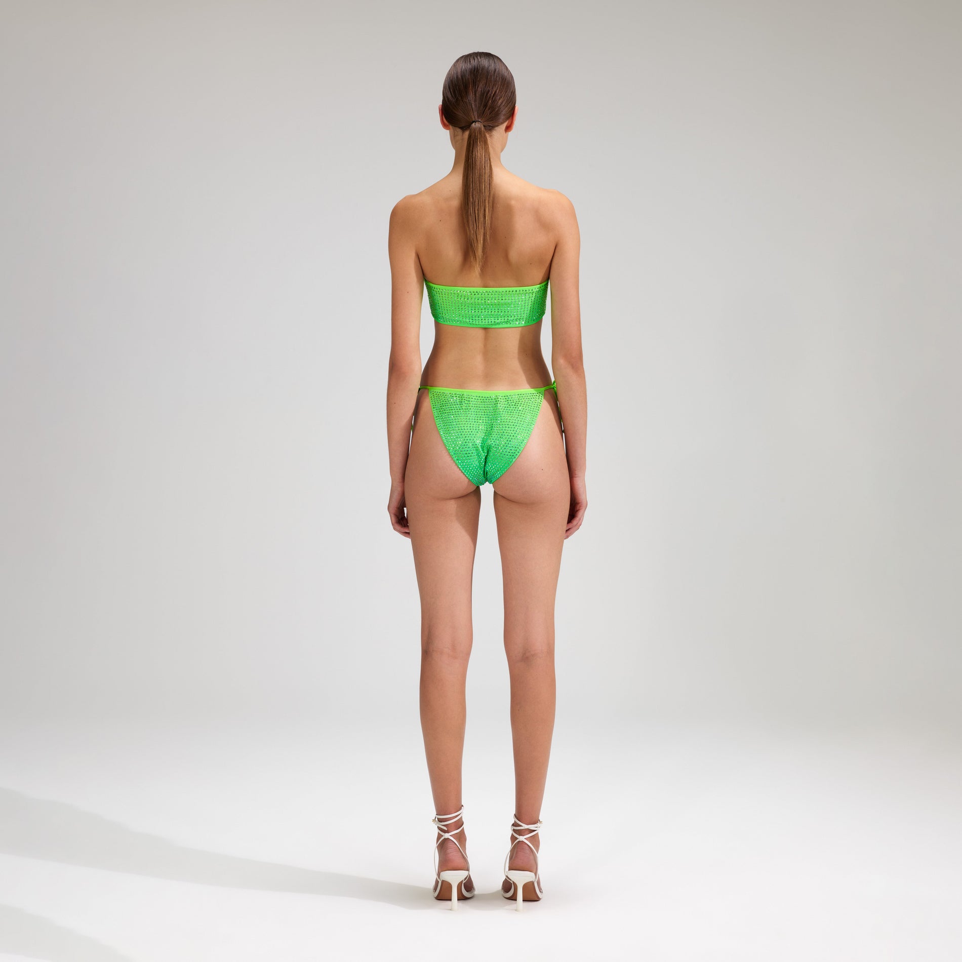 A woman wearing the Green Rhinestone Tie Side Bikini Brief