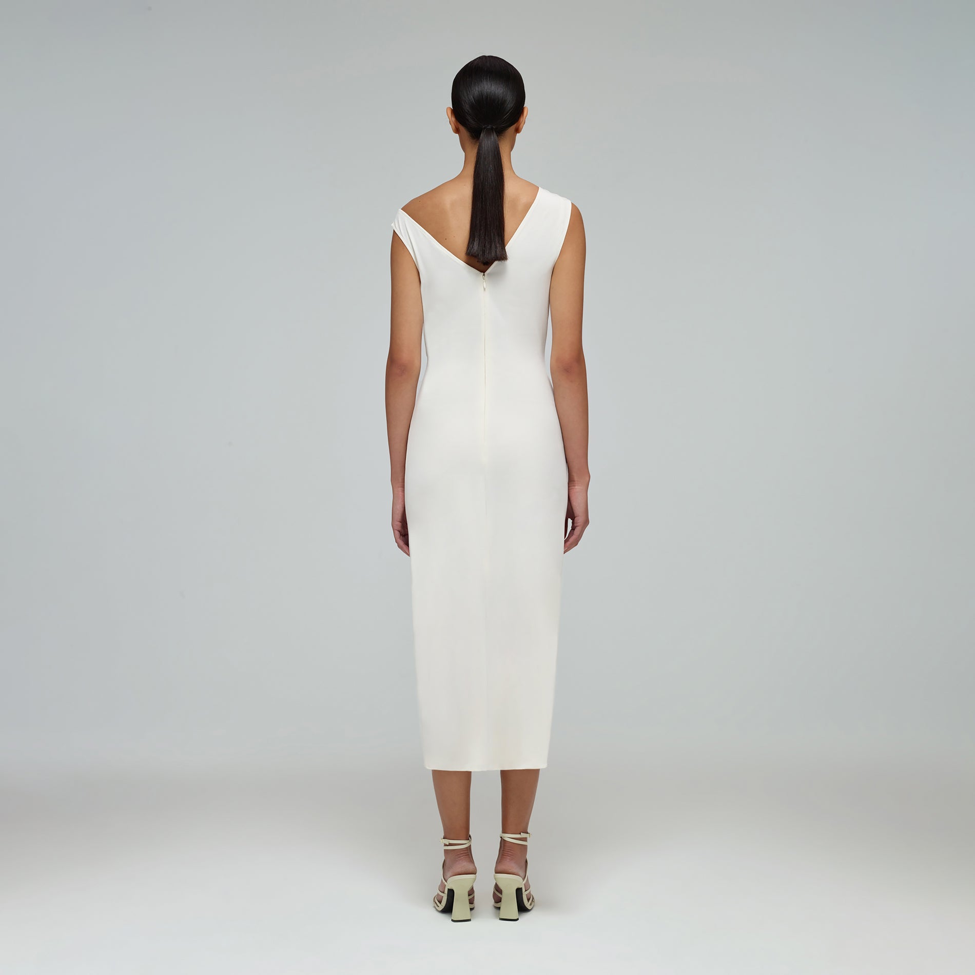 A woman wearing the Ivory Jersey Gathered Asymmetric Midi Dress