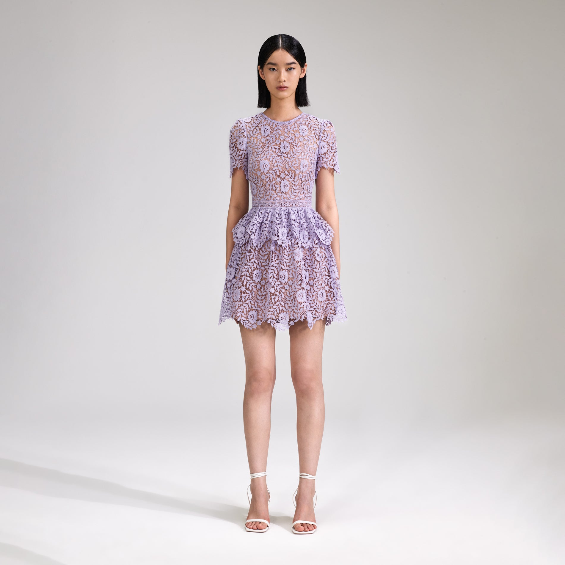 A woman wearing the Lilac Rose Lace Peplum Mini Dress