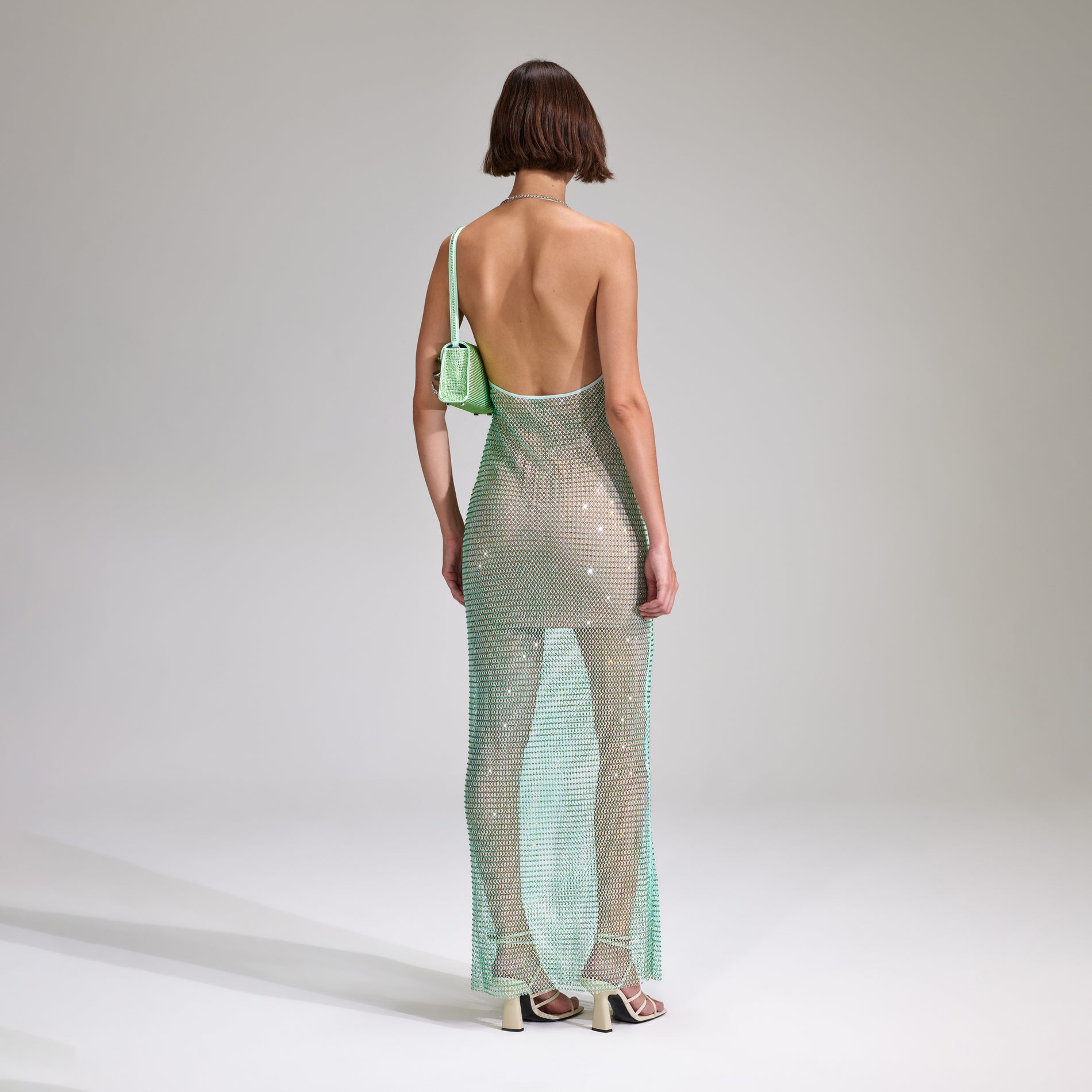 A woman wearing the Mint Rhinestone Fishnet Cowl Maxi Dress