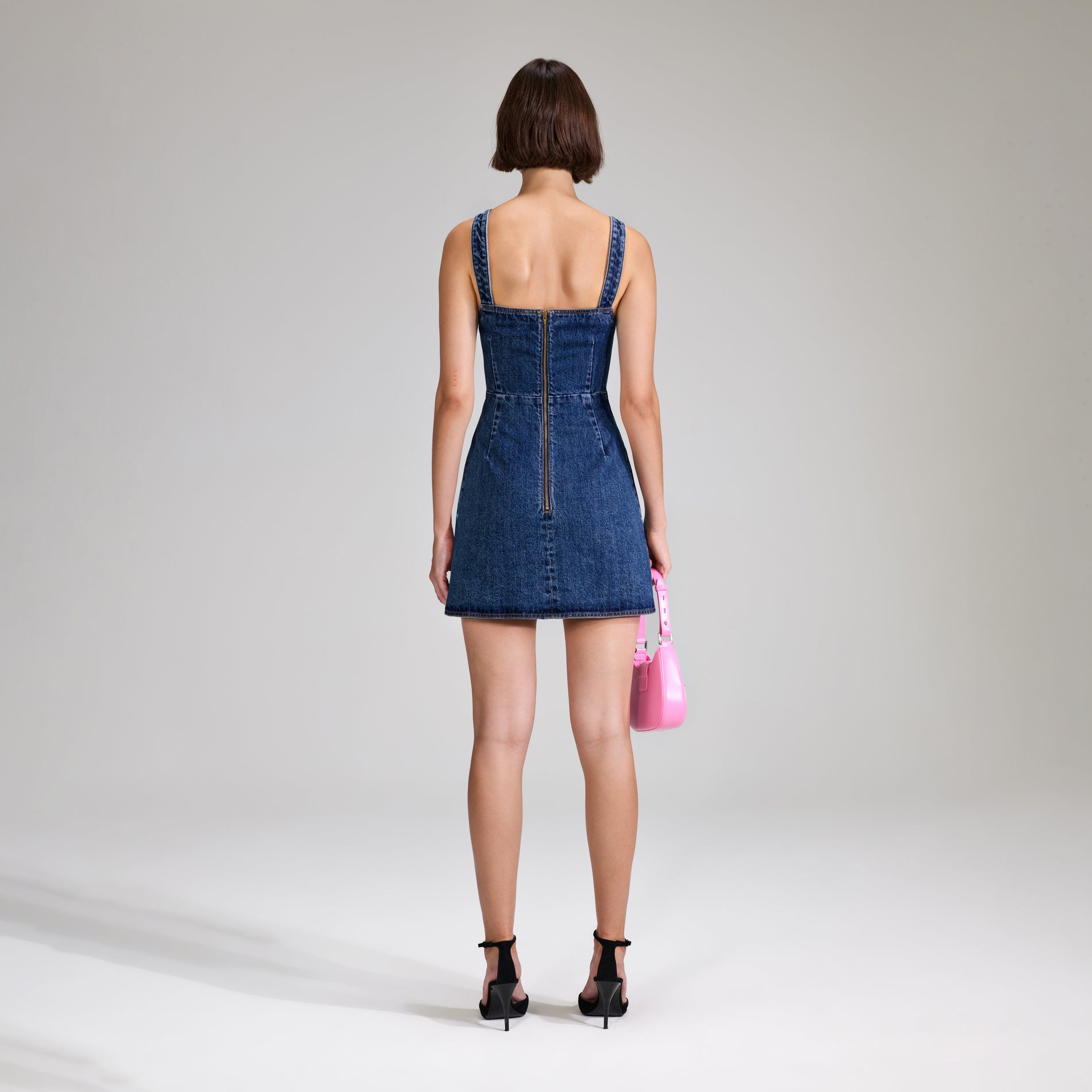 A woman wearing the Denim Mini Dress With Bows