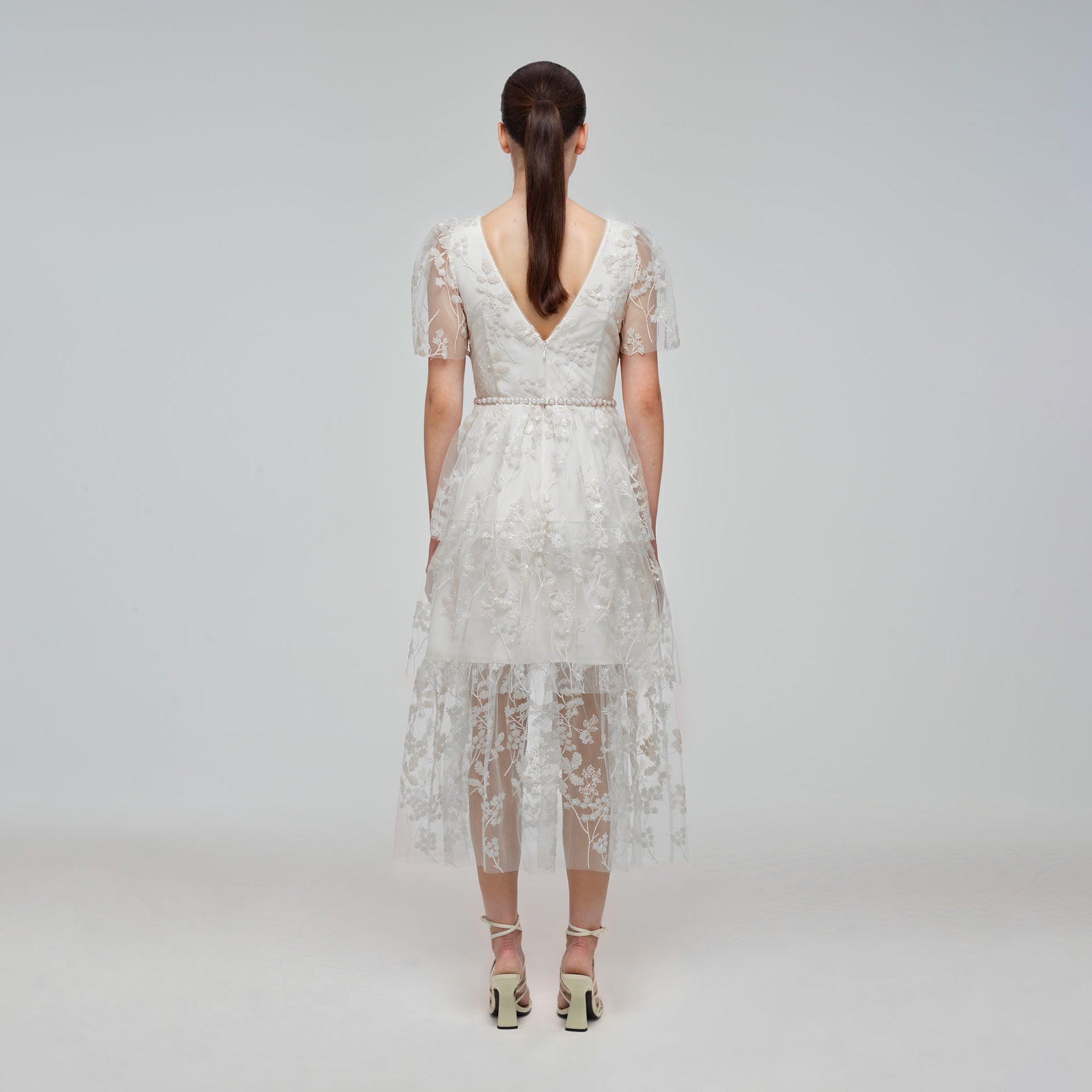 A woman wearing the Ivory Blossom Sequin Two Tier Midi Dress